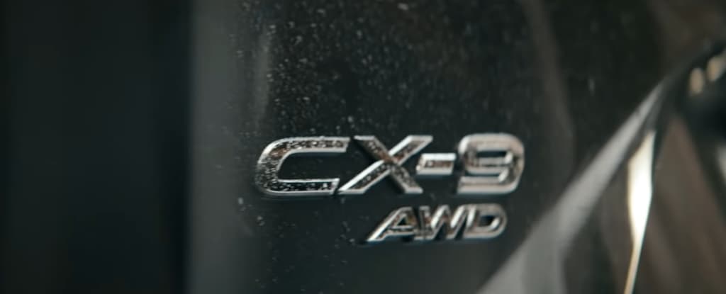 Close-up of the Mazda CX-9 AWD emblem on a car's fender