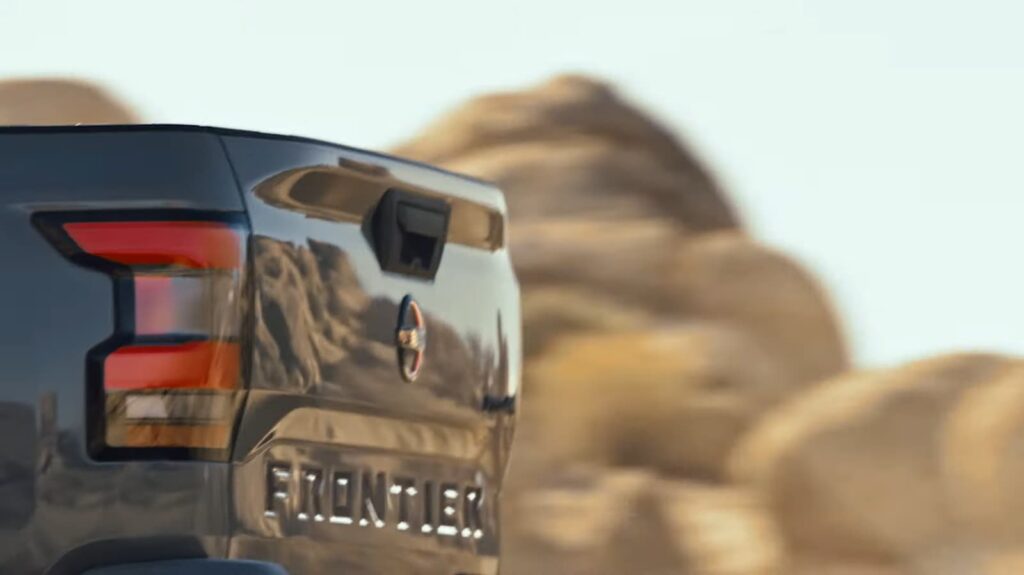 Close-up of a pickup truck's tailgate with "Frontier" emblem and rocky background