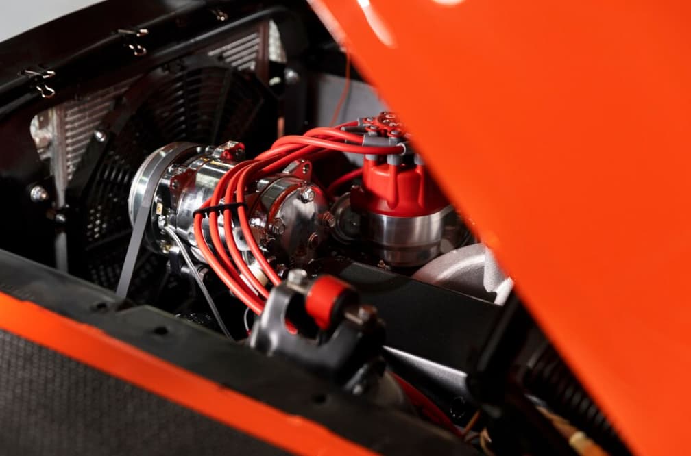 Classic orange car engine with red ignition wires and chrome parts